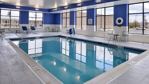 Una piscina interior con agua cristalina, una silla de salvavidas y un cartel de elevador para la piscina.