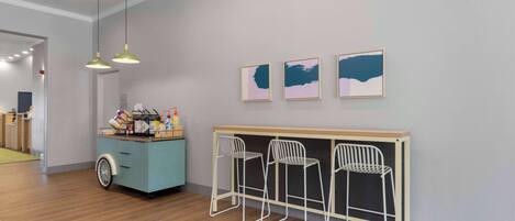 A modern room with a wooden floor, a desk with three white chairs, and three framed artworks on the wall.