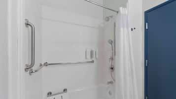 Une salle de bain avec une douche, des barres d’appui et une porte bleue.