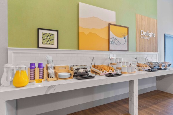 A breakfast buffet with various food items and a sign that reads "Delight in the day."