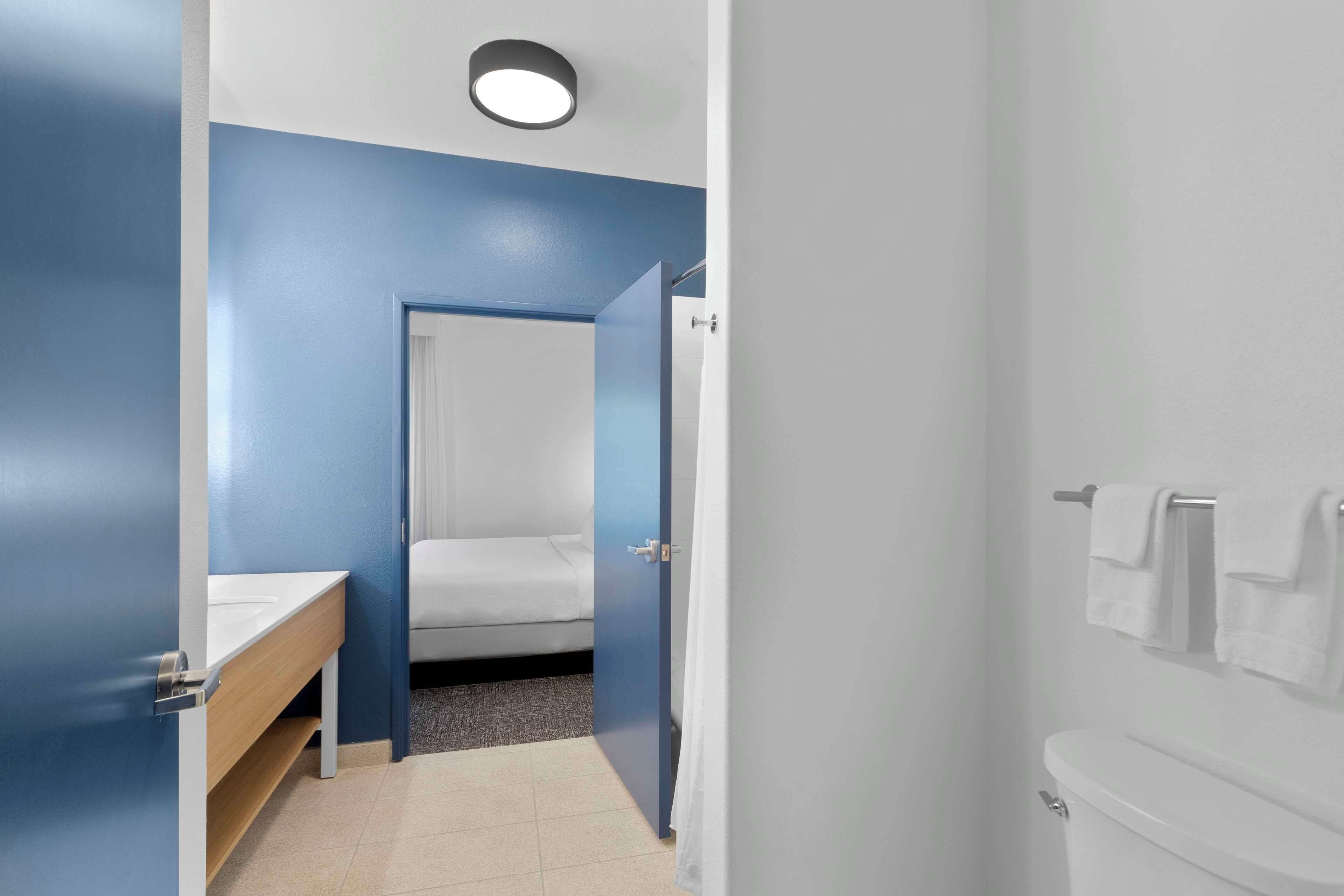 A modern bathroom with a blue accent wall, a white sink, a toilet, and a shower area.