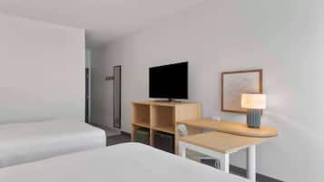 Une chambre d’hôtel avec un lit, un bureau doté d’une lampe, une télévision et un tableau encadré au mur.