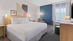 A hotel room with a large bed, bedside lamps, a desk, a chair, and a window with curtains. - Spark by Hilton San Antonio Dominion (San Antonio)