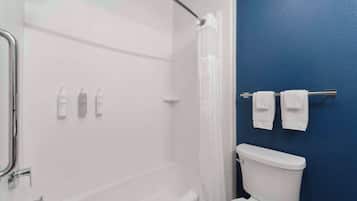 Un baño con una bañera blanca, un inodoro blanco y una pared azul.