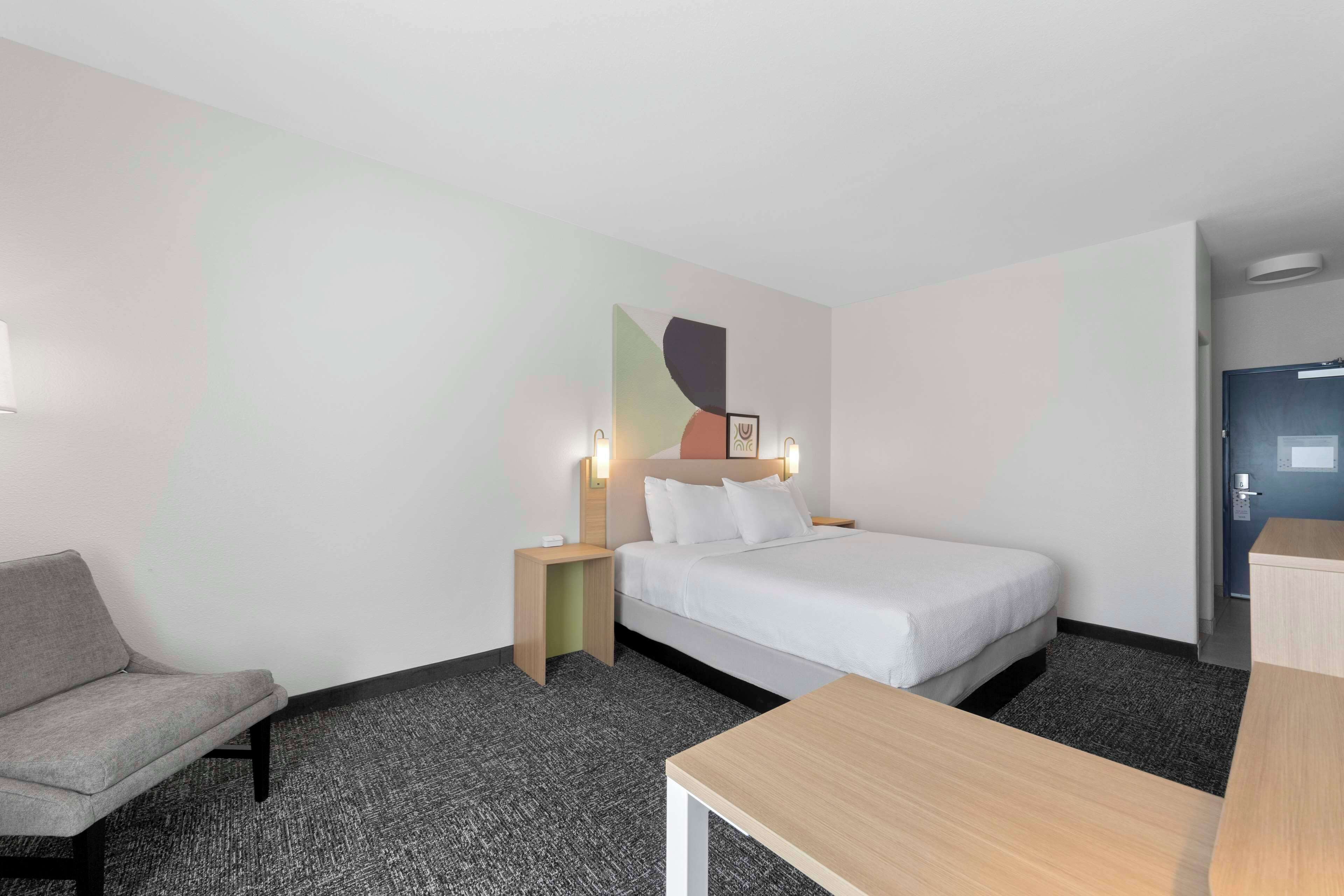 Une chambre d’hôtel avec un lit, un bureau, une chaise et une table de chevet.