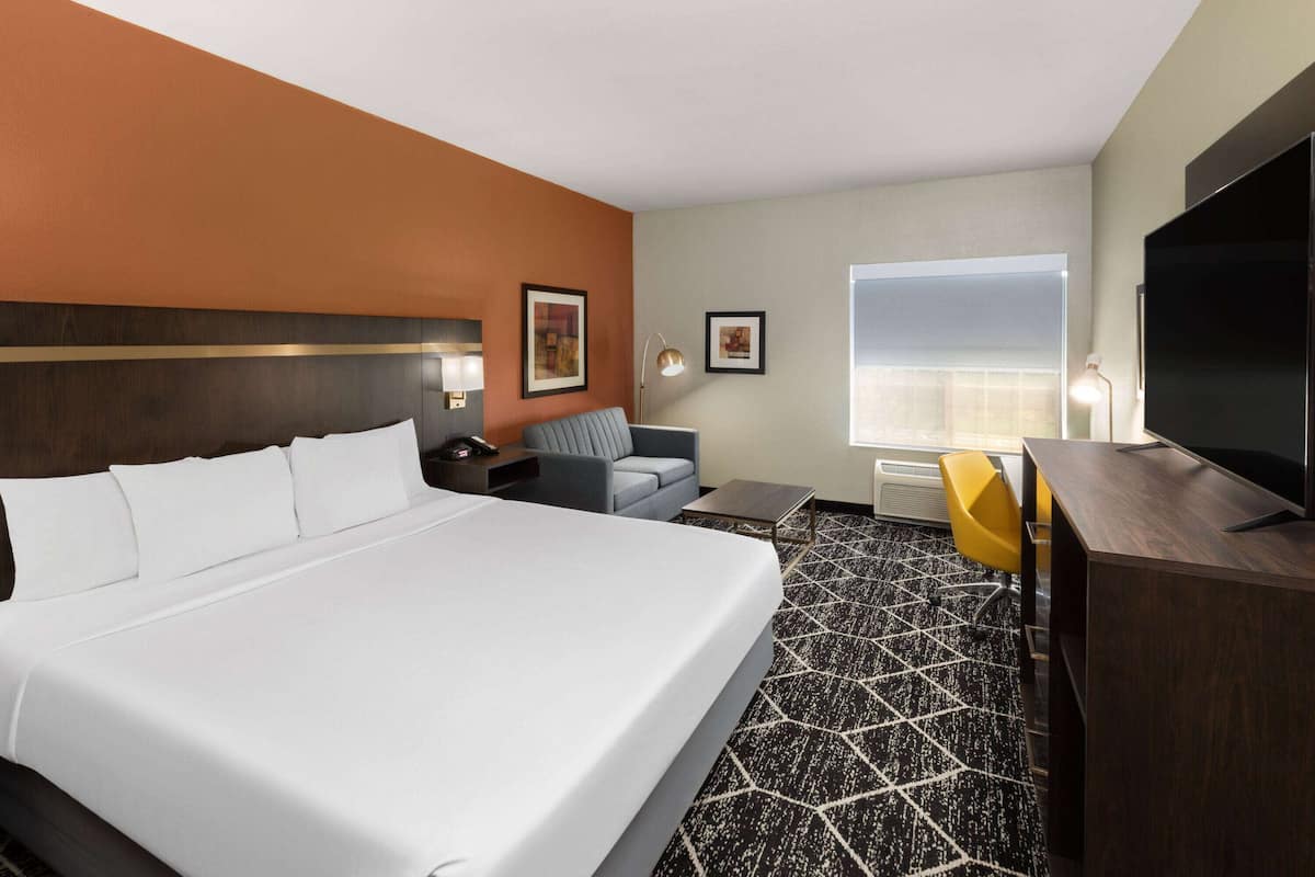 A hotel room with a large bed, a desk, a chair, and a TV.