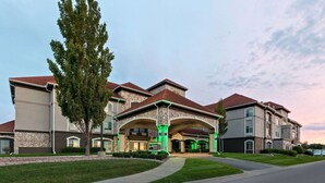 A multi-story residential building with a stone facade, green landscaping, and a clear sky. - La Quinta Inn & Suites by Wyndham Olathe (Olathe)