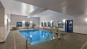An indoor swimming pool with a clear blue water, surrounded by lounge chairs and a sunlit ceiling. - La Quinta Inn & Suites by Wyndham Olathe (Olathe)