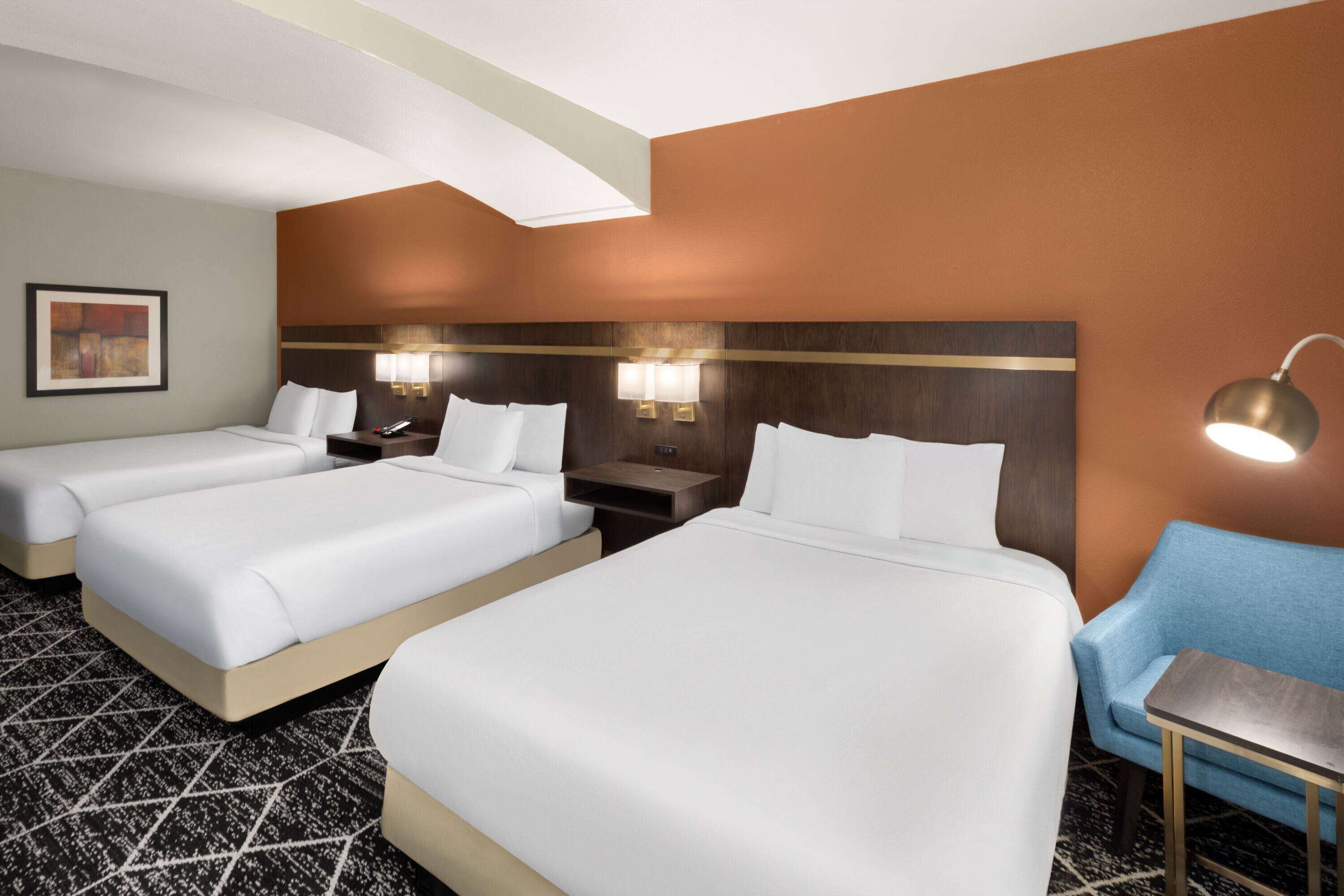 Habitación de hotel con dos camas, un escritorio, una silla y una mesita de noche.