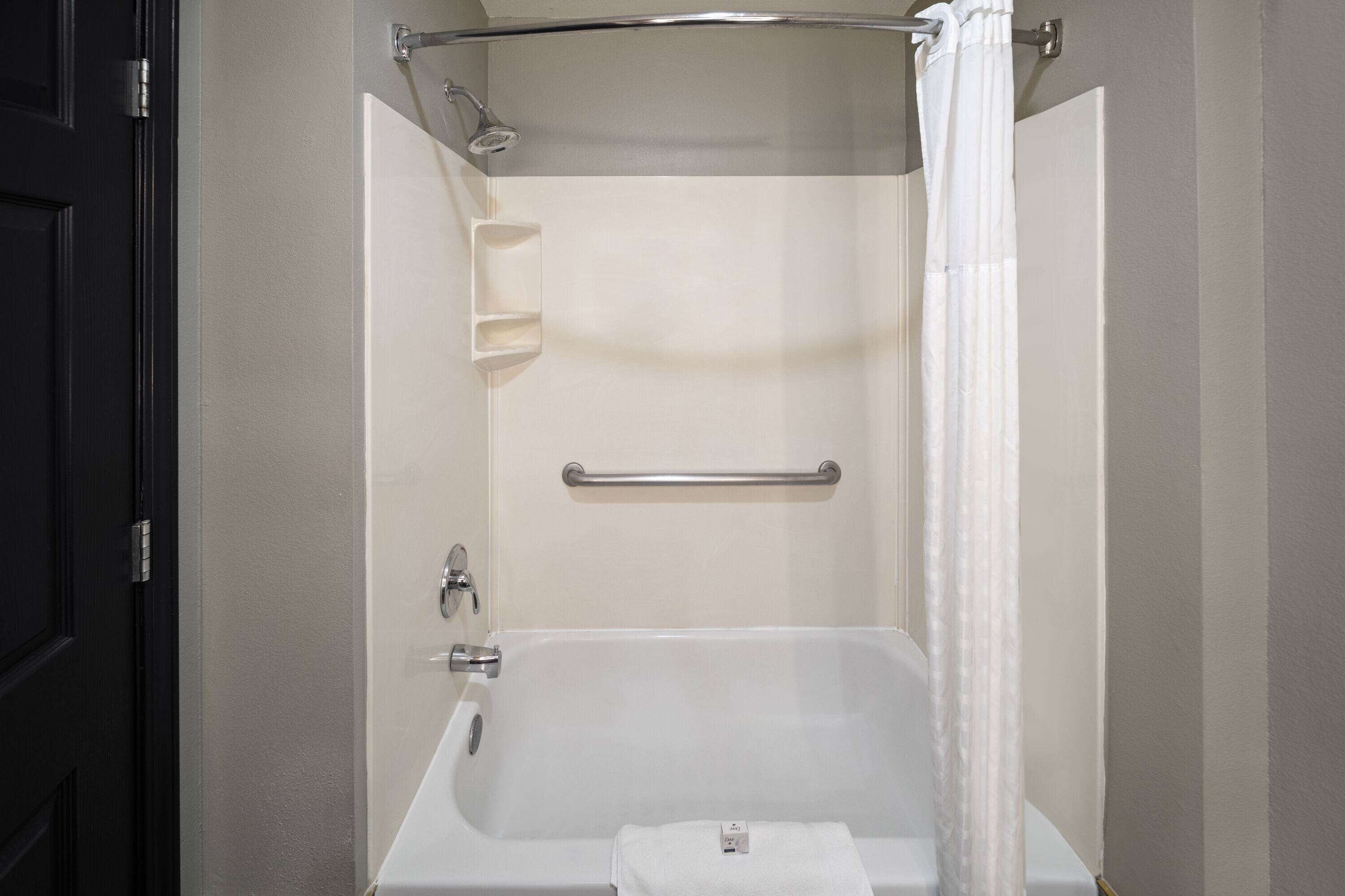 A modern bathroom with a bathtub, a shower, a towel rack, and a soap dish.