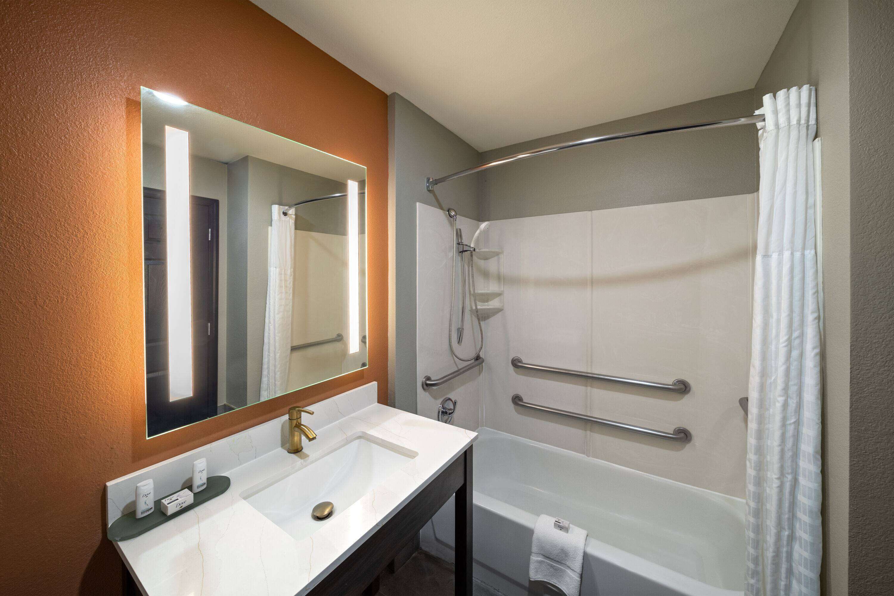 Un baño con lavamanos blanco, espejo y bañera.