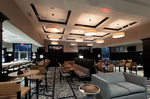 A hotel lobby with multiple seating areas, including sofas and tables, and a patterned carpet.