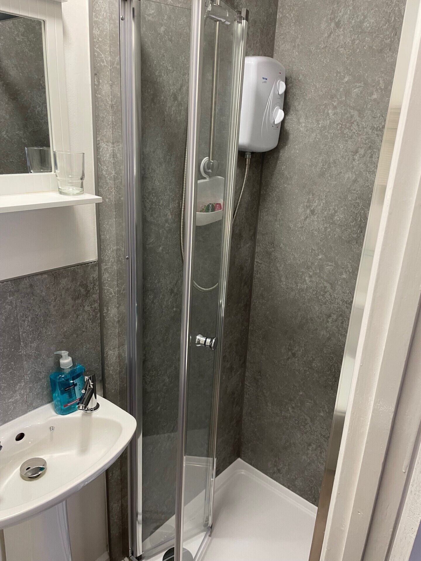 A bathroom with a glass shower enclosure, a white sink, and a handheld showerhead.