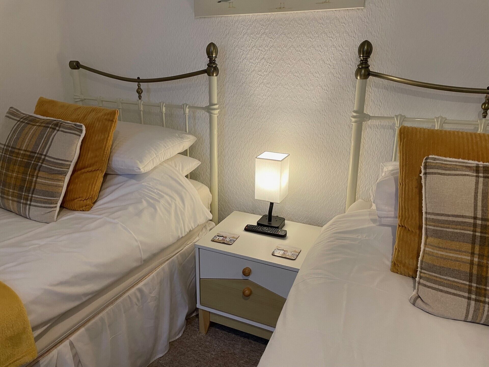 Une chambre avec deux lits jumeaux, une table de chevet, une lampe et une télécommande.