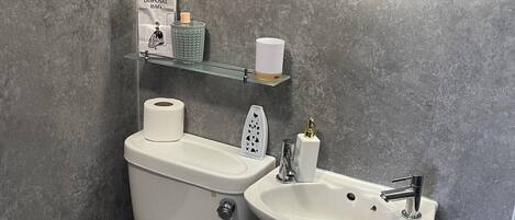 A bathroom with a toilet, bidet, sink, and a mirror.