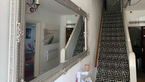A bathroom with a large ornate mirror, a black and white patterned shower curtain, and a chandelier.