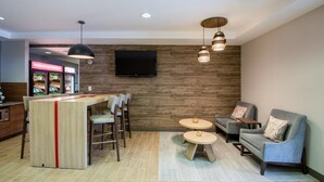 Un interior moderno con una zona de bar, asientos y un televisor de pantalla plana montado en una pared de madera.