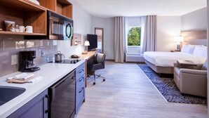 Habitación de hotel con kitchenette, una cama, escritorio y vistas al exterior.