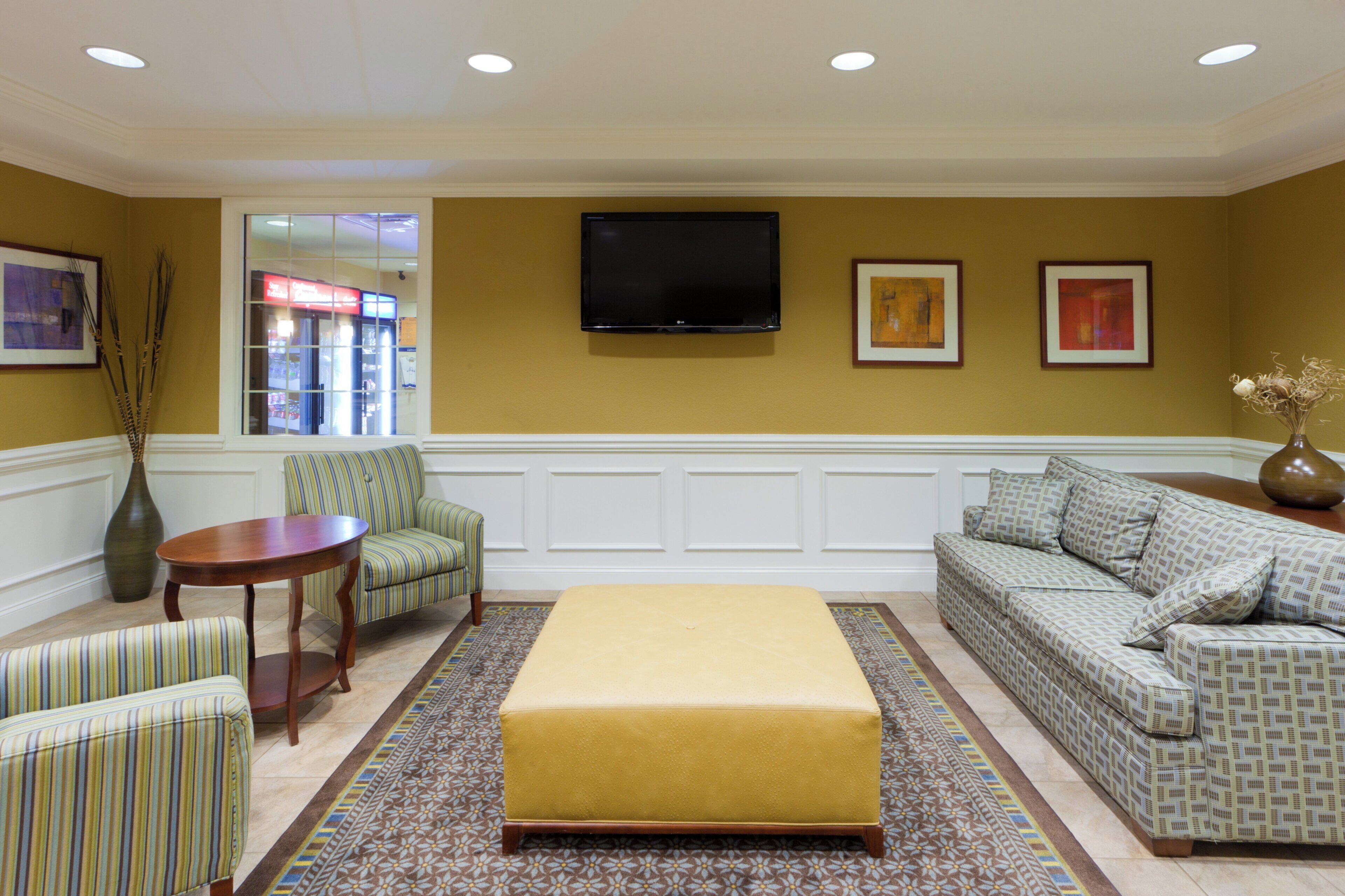 Una sala de estar con sofá, sillones, una mesa de centro, televisor de pantalla plana y obras de arte en las paredes.