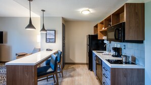 Una cocina moderna con armarios de madera, un refrigerador negro y una encimera blanca.
