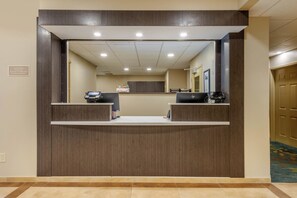 Een receptiebalie met twee gedeelten, een aan de muur bevestigd telefoon en een bord met de openingstijden.