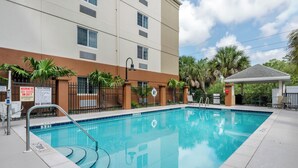 A swimming pool with a lifeguard chair, a no diving sign, and a pool rules sign.