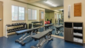 A gym with exercise equipment, benches, dumbbells, and a mirror.