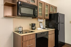 Uma cozinha compacta com micro-ondas, cafeteira e máquina de lavar louça.