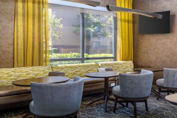 A modern interior with a sofa, two round tables, and four chairs. - SpringHill Suites by Marriott Roseville (Roseville)