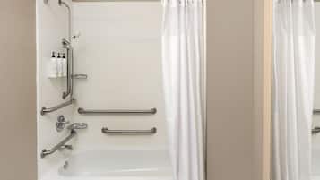 Un baño con una bañera blanca, barras de apoyo y una cortina de ducha.