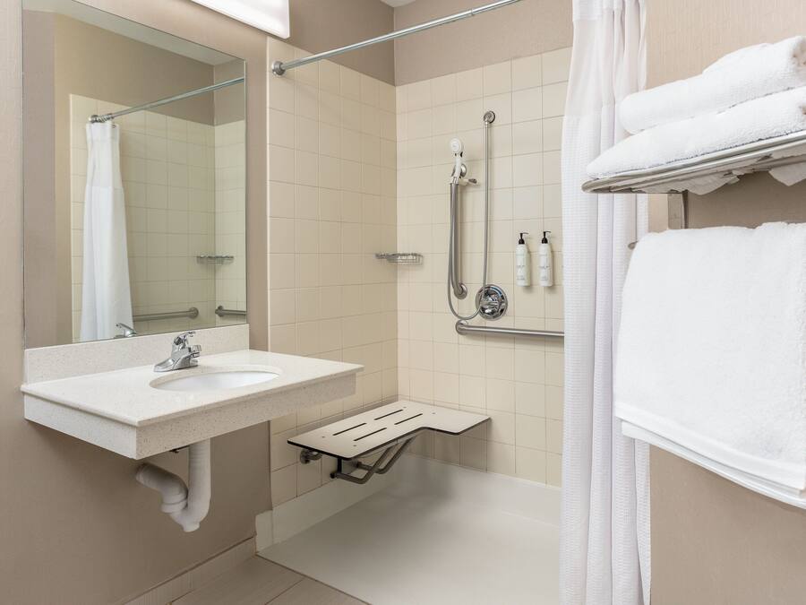 Ein Badezimmer mit Waschbecken, Spiegel, Dusche und Handtuchhalter.