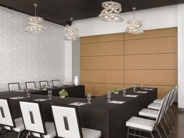A conference room with a long table set for a meeting, surrounded by white chairs.