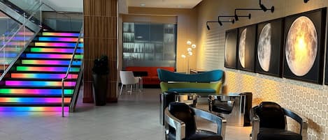Eine moderne Lobby mit Treppe, Sitzgelegenheit und Wandbildern.