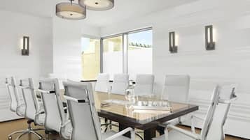 A conference room with a long table, white chairs, and pendant lighting.