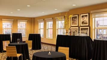 A conference room with round tables, black tablecloths, and chairs.