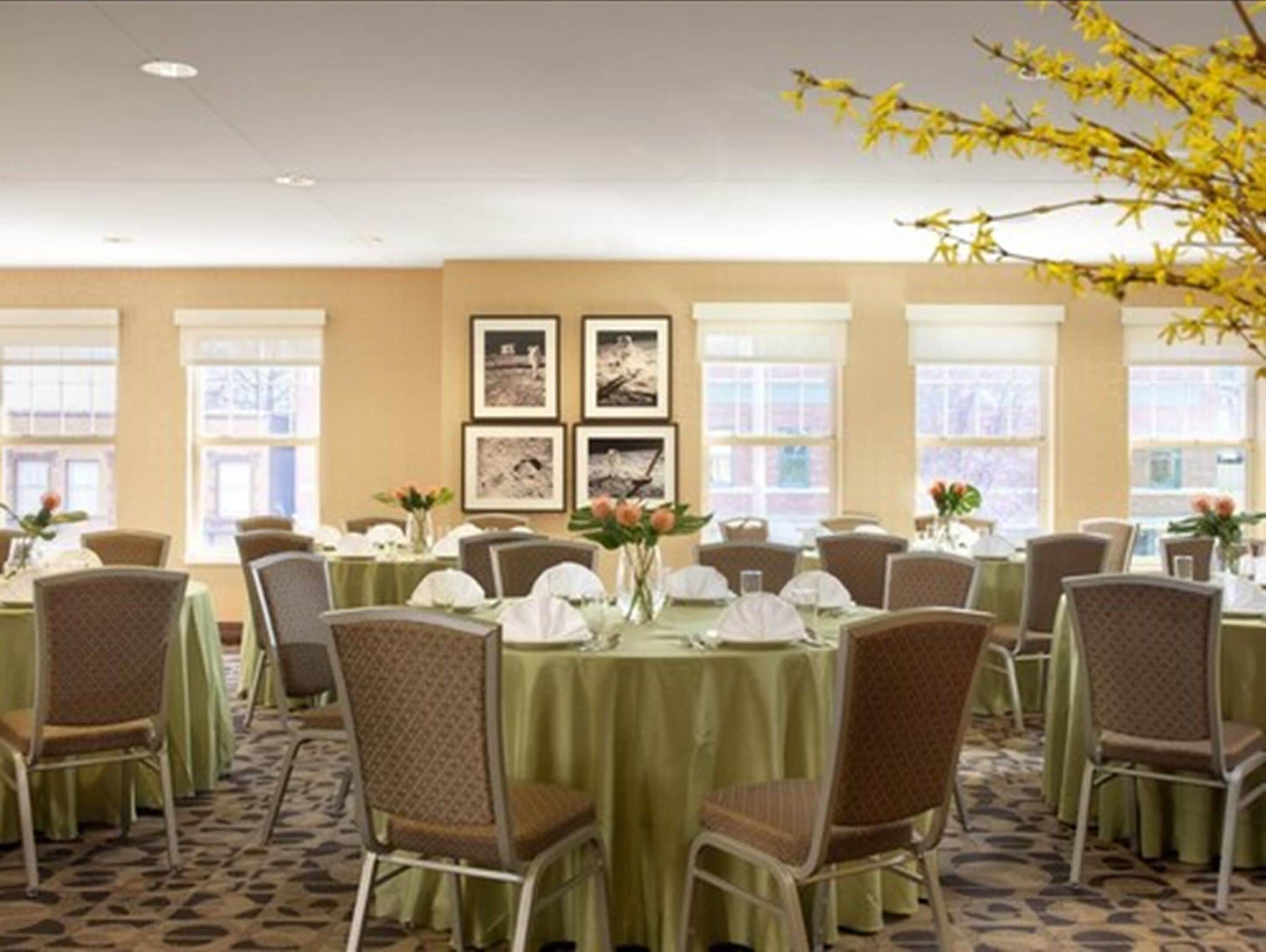 A conference room with round tables, chairs, and framed pictures on the wall.