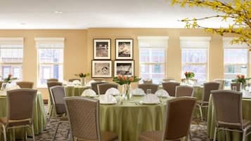 A conference room with round tables, chairs, and framed pictures on the wall.