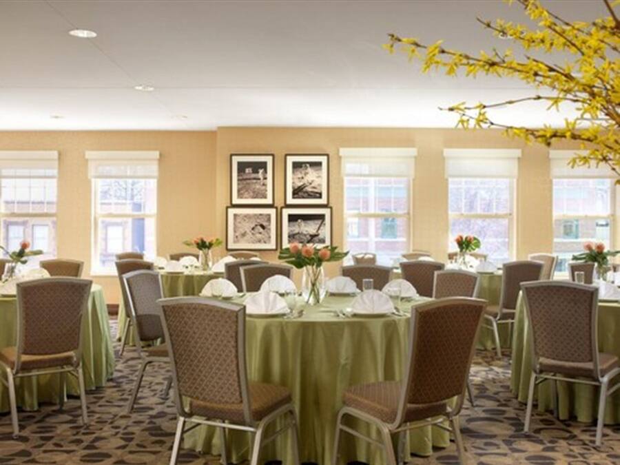 A conference room with round tables, chairs, and framed pictures on the wall.