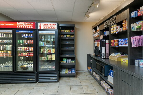 A convenience store with refrigerated beverage coolers, snack shelves, and a section for household items.