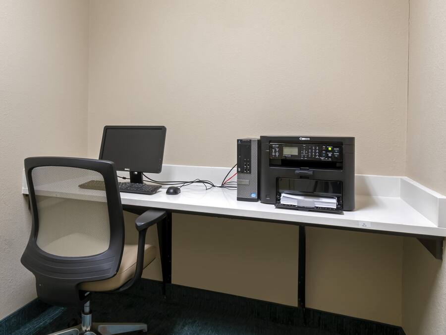 A small office space with a desk, chair, computer, printer, and keyboard.