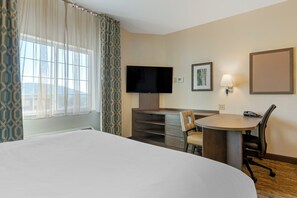 A hotel room with a large bed, a desk with a chair, a flat-screen TV, a lamp, and a framed picture on the wall. - Candlewood Suites Reading by IHG (West Reading)