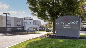 A hotel sign for Candlewood Suites, part of the IHG hotel chain, with a modern building in the background. - Candlewood Suites Reading by IHG (West Reading)