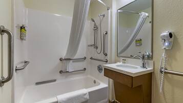 Un baño con bañera, lavamanos, espejo y secador de pelo.