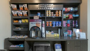 A kitchenette area with a microwave, coffee maker, and various snacks and beverages. - Candlewood Suites Reading by IHG (West Reading)
