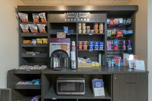A kitchenette area with a microwave, coffee maker, and various snacks and beverages.