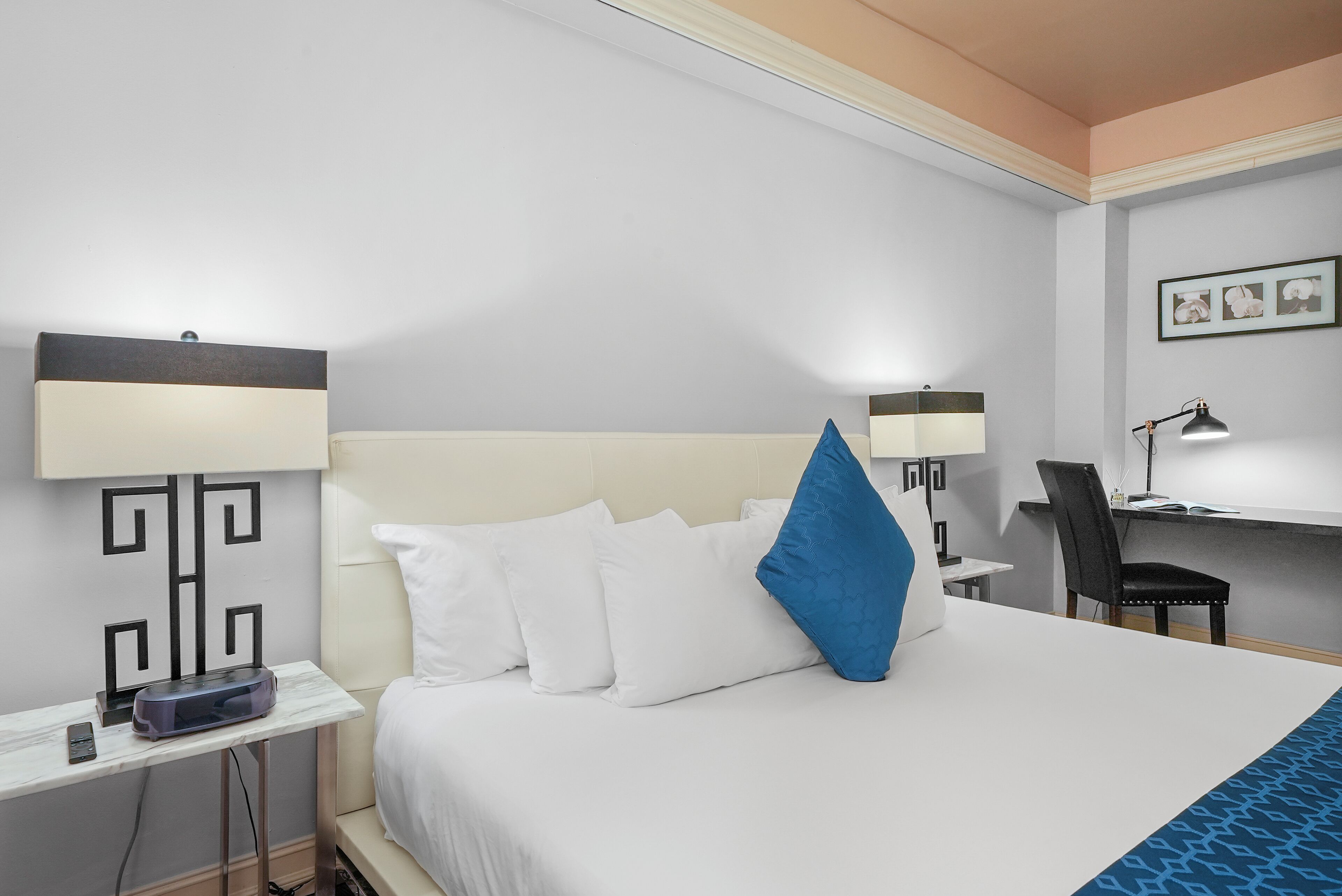 Ein Hotelzimmer mit einem Bett, zwei Nachttischen, einem Schreibtisch, einem Sessel und einer Lampe.