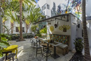 An outdoor patio area with seating, tables, and hanging plants. - Riviera Hotel South Beach (Miami Beach)