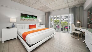 A modern hotel room with a large bed, a desk, and a balcony with outdoor seating. - Riviera Hotel South Beach (Miami Beach)