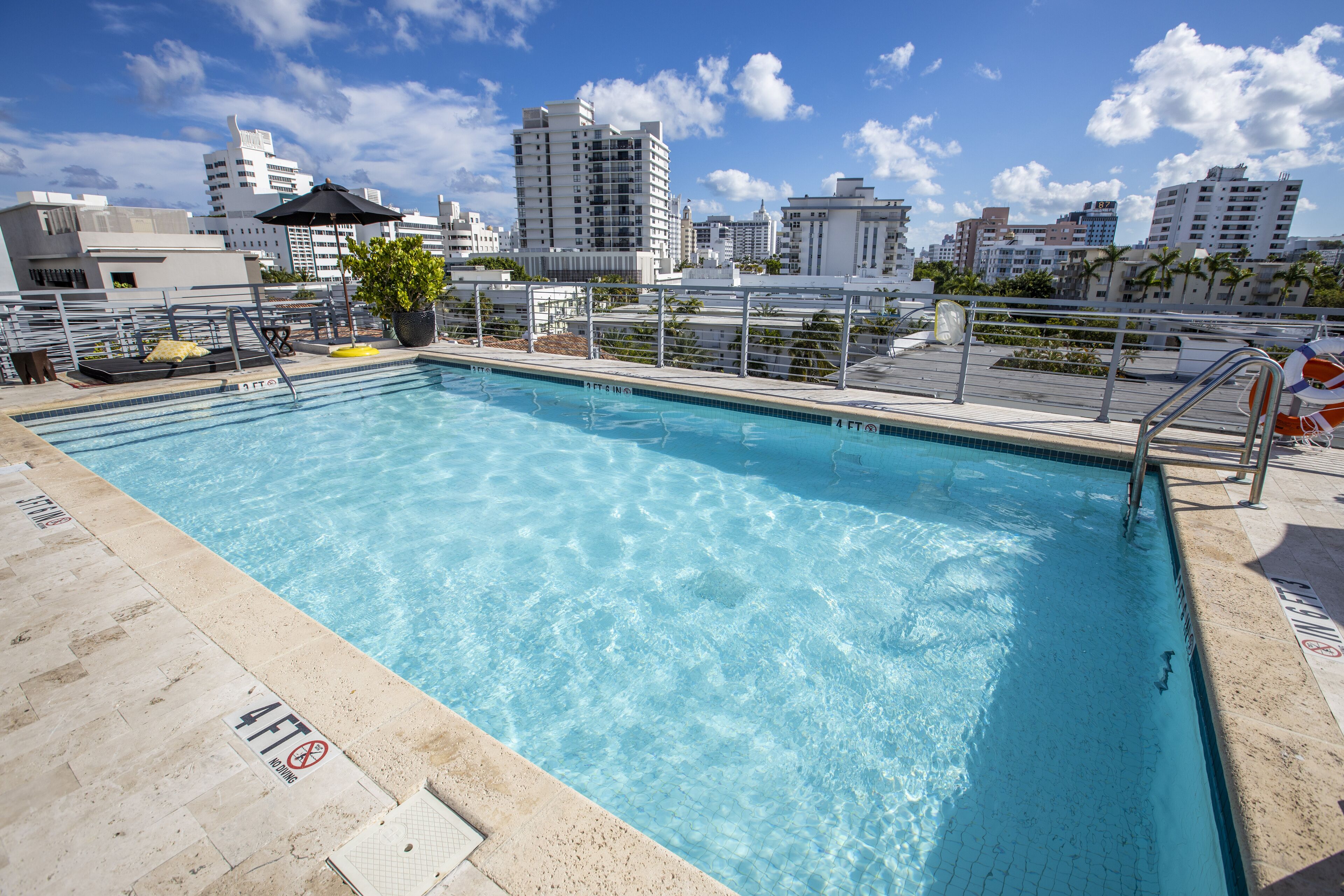 Una piscina sul tetto con acqua cristallina, circondata da una ringhiera metallica e vista sulla città.