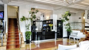 A modern lobby with a reception desk, a staircase, and potted plants. - Riviera Hotel South Beach (Miami Beach)